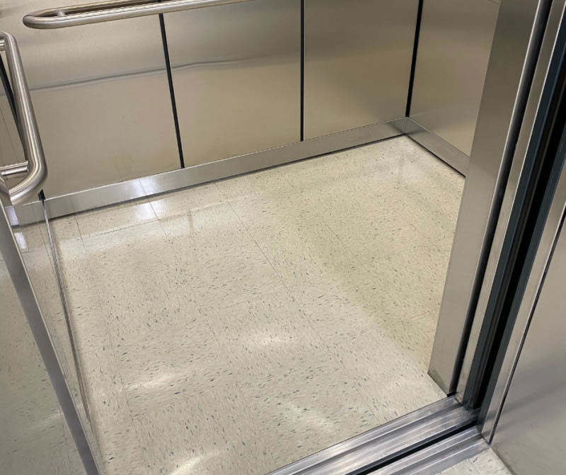 Light tiled floor inside a stainless-steel elevator.