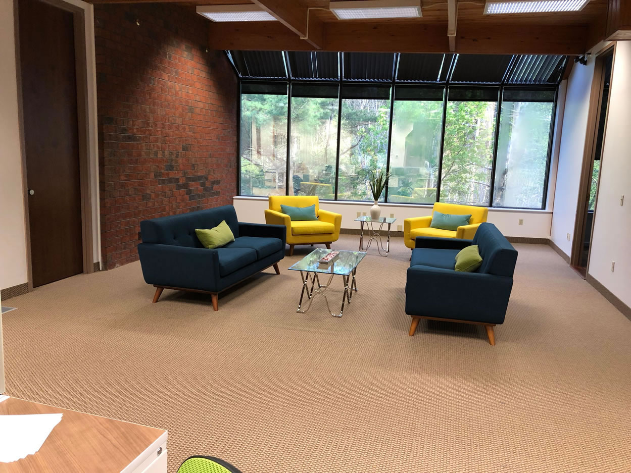 Office lounge with blue sofas, yellow chairs and large windows.