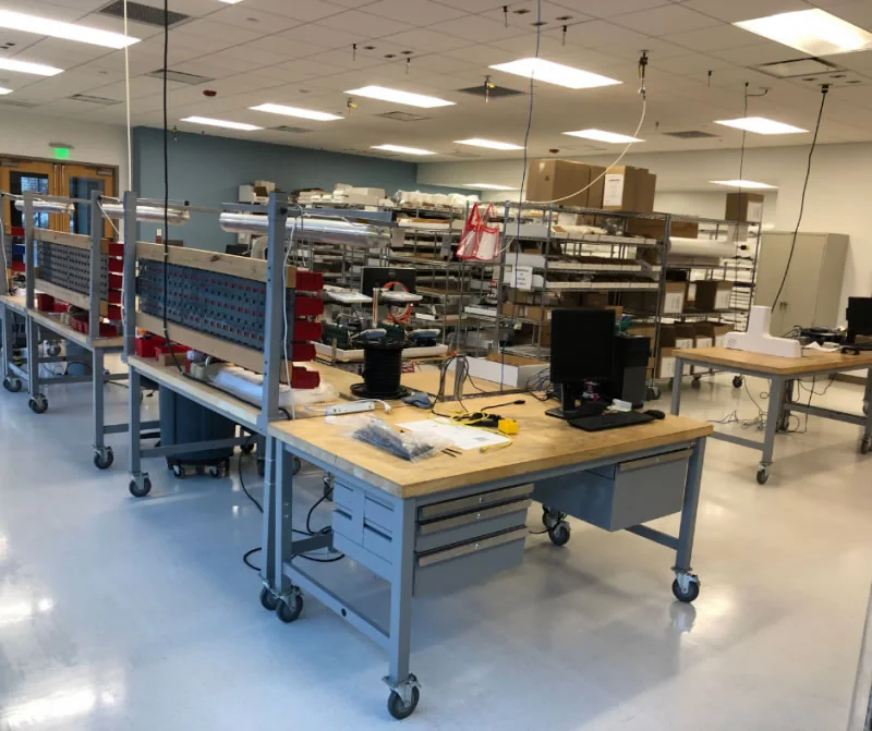 Industrial workspace with workbenches, shelving, equipment and a reflective floor.