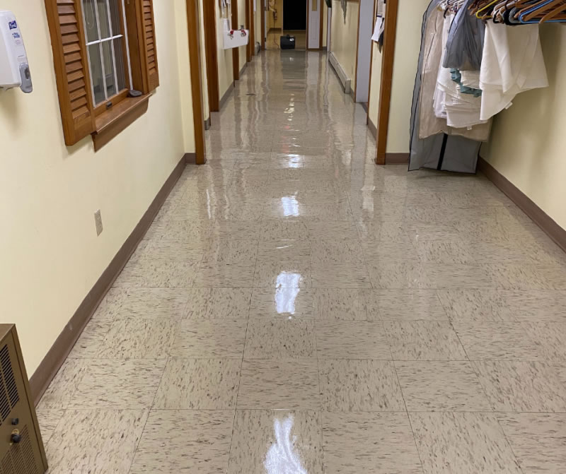 Reflective light tile floor in a hallway with wood-trimmed doorways.